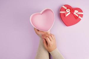 two hands hold a paper open red box in the shape of a heart photo