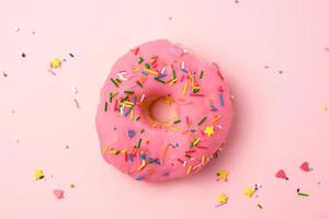 pink round donut with colored sprinkles photo