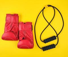 pair of red leather boxing gloves and black trainer hand expander photo