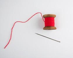 wooden reel with red wool thread and a large needle photo