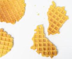 baked round belgian waffles on white background, broken pieces and crumbs photo