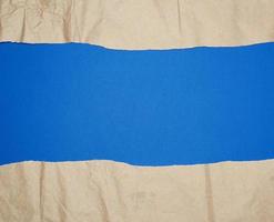 torn brown sheet of paper on a blue background, full frame photo