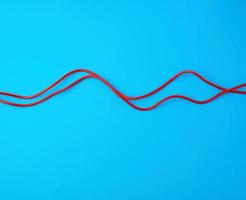 fragment of a red jump rope for sports on a blue background photo