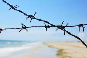 Fencing of the sea shore with barbed iron wire photo