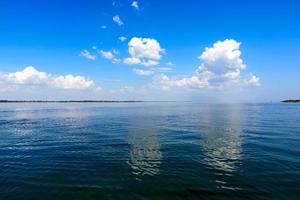 view of the sea with white fluffy clouds photo