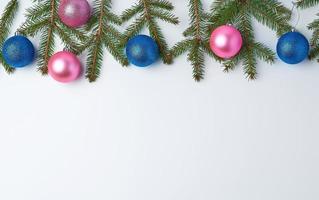 green spruce branches, pink and blue shiny Christmas balls on a white background, festive backdrop photo