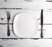 empty white ceramic plate with a fork and knife photo