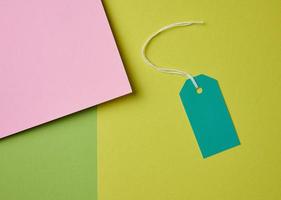 Blank pink cardboard tag on white rope, green background photo