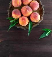 fresh ripe peaches in a round iron plate photo