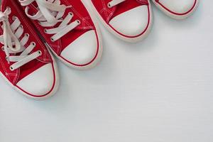 dos pares de zapatillas rojas juveniles sobre una superficie de madera blanca foto