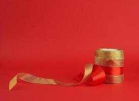 twisted golden and red silk shiny ribbon on a red background photo