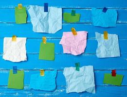 muchos pedazos de papel multicolor rotos pegados con cinta adhesiva sobre un fondo de madera azul foto
