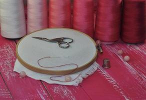 tools for needlework thread and red tones on a wooden table photo