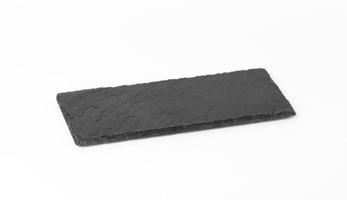 tablero de piedra de pizarra negra rectangular aislado sobre fondo blanco, utensilios para servir comida foto