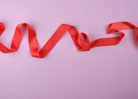 curled red satin ribbon on a purple  background photo