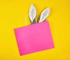 bolsa de compras de papel rosa rectangular con un asa blanca sobre un fondo amarillo foto