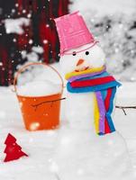 snowman with a bucket on his head on white snow photo