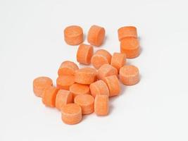 orange pills on white background, vitamin C photo