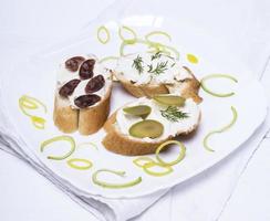 Sándwiches con queso cremoso, chorizo, aceitunas y eneldo foto