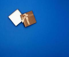 open brown square cardboard empty box, item lies on a blue classic background color photo