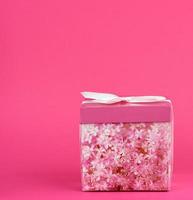 closed pink cardboard box with a bow on a pink background photo