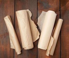 four rolled rolls of brown parchment paper on a wooden background photo