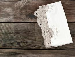 toalla blanca de encaje textil de cocina doblada sobre una mesa de madera gris de tablas antiguas foto