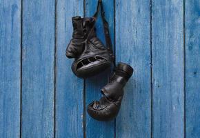 Black vintage boxing gloves hanging on an old rusty nail photo