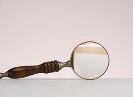 wooden magnifier on a white background. The concept of uncertainty and the search for solutions, doubts photo