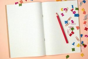 open checked notebook and red wooden pencil photo