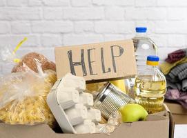cardboard box with various products, fruits, pasta, sunflower oil in a plastic bottle and preservation photo