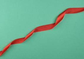 twisted red silk ribbon, green background, top view photo