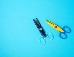 two pieces of plastic baby scissors for scrapbooking on a blue background, photo