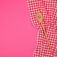 wooden spoon with a carved face on a red kitchen towel photo