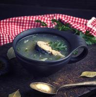 soup with mackerel in a brown clay plate and an iron spoon photo