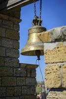 a copper bell hanging on a chain in a bell tower photo