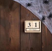 figuras de araña negra y reloj retro de madera hecho de bloques con la fecha del 31 de octubre foto