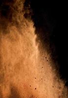 flying brown cocoa particles on a black background. Powder flies up photo