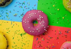 round different donuts with sprinkles on a bright multi-colored background photo