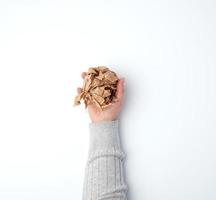 hand holds a crumpled sheet of brown paper on a white background photo