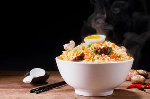 a bowl of instant noodles or pasta Delicious hot soup, Thai, Chinese, Japanese food with chopsticks and condiments, lime, chili, shiitake mushrooms, arranged on table isolated on black background. photo