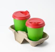 disposable green cups with red plastic lid stand in holder on white background photo