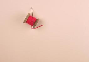 wooden reel with red wool thread and a large needle photo