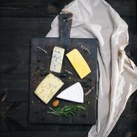 pieces of different cheeses on a brown wooden board photo