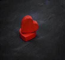 dos corazones de madera roja sobre un fondo negro foto