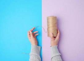 female hands holding a skein with brown eco thread on a colorful background photo