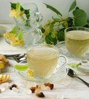 transparent cup with tea from ginger  and linden on a white wooden board photo
