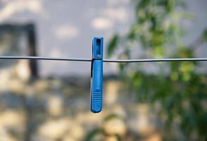 blue plastic clothespin hanging on a metal wire photo