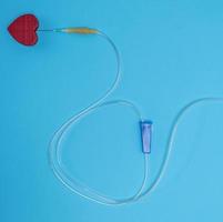 empty plastic dropper with needles and red heart on blue background photo