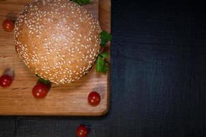 deliciosa hamburguesa fresca en una tabla de cortar y tomates cherry foto